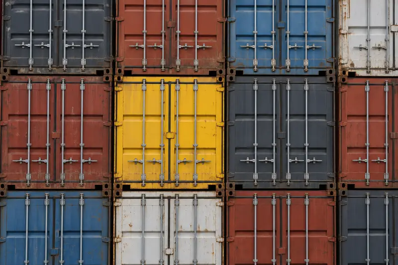 Stacked container doors, one yellow container among grey, red and blue ones